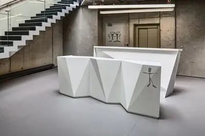 Reception desk made from Corian; its shape is linked to the design of the exterior facade